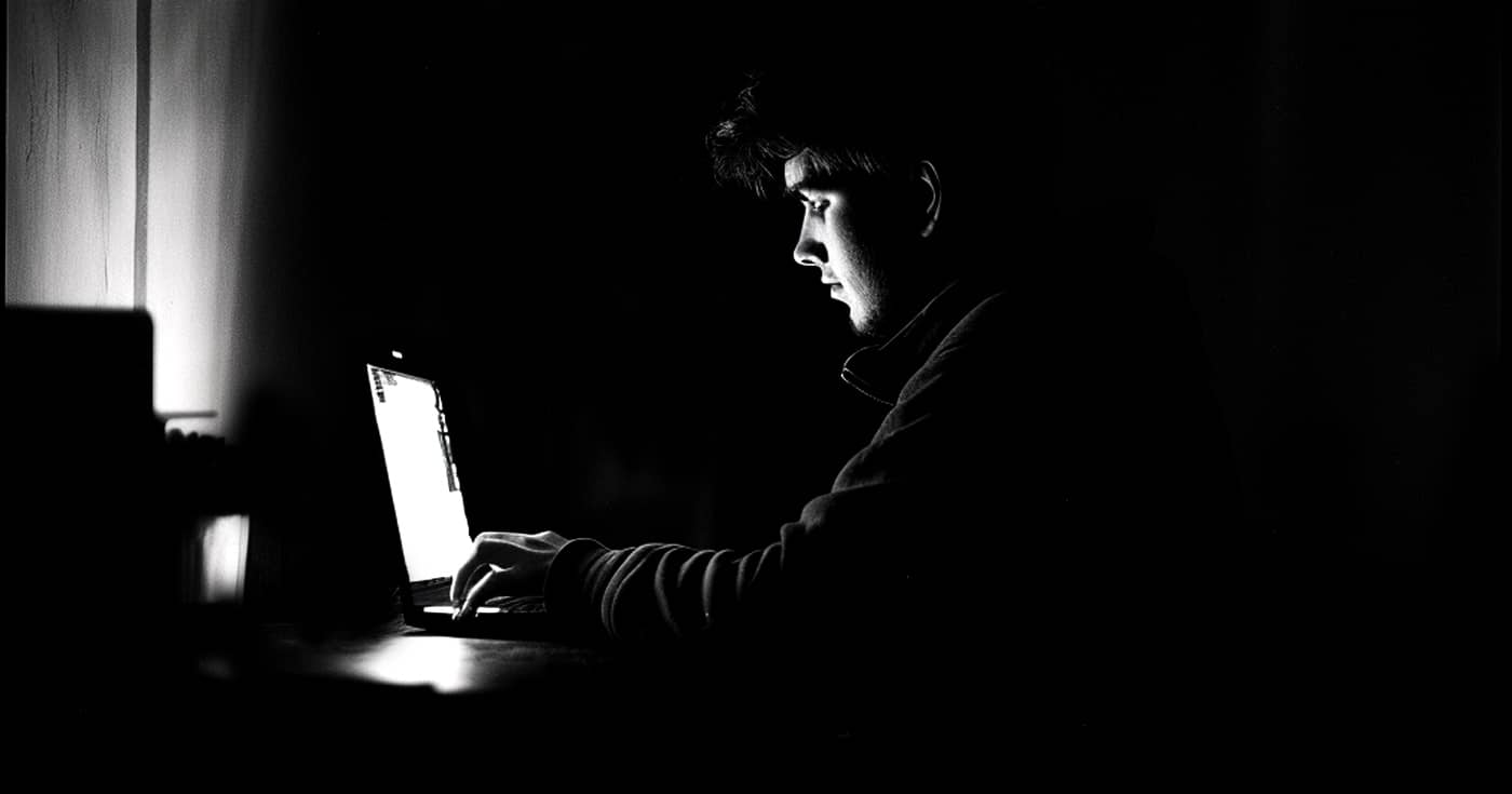 Man zit op laptop in het donker